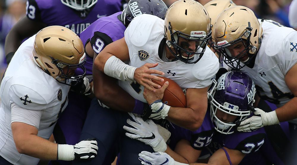 John Carroll ballcarrier all wrapped up by players in purple.